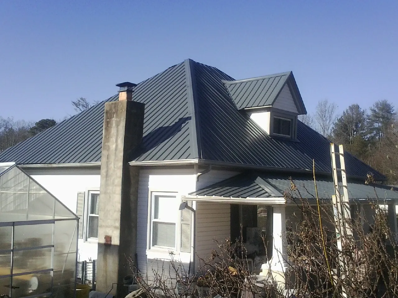 Dark blue standing seam metal roof on a white farmhouse with dormer — Slate & Tile Roof Repair by Roofing Brothers in Cordele