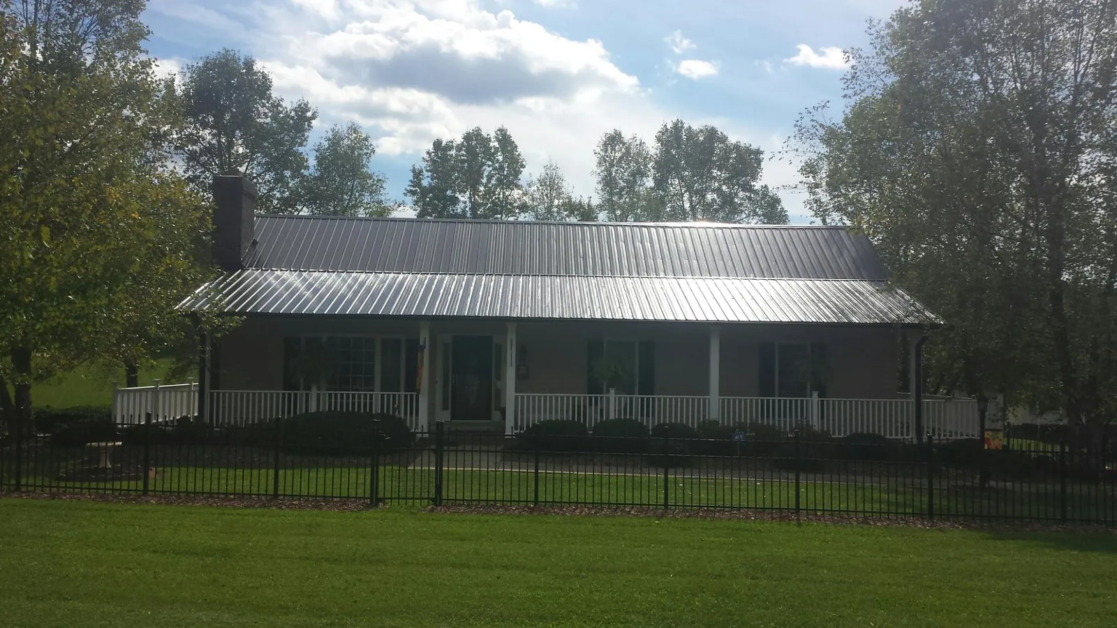 Gray metal roof on a brick ranch with a full width front porch — Gutter Guard Installation work by our crew in Cordele